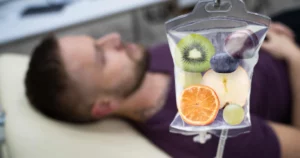 Man receiving IV Therapy in Riverside, CA with a nutrient-rich infusion bag containing fruits symbolizing vitamins and hydration.